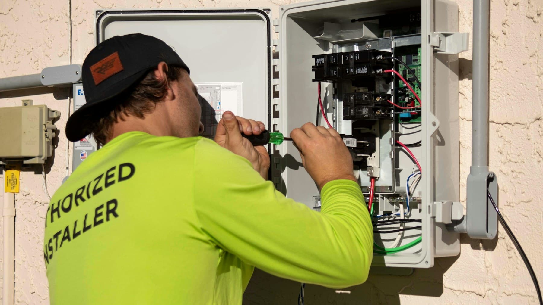 Electrician in a hi-vis shirt working on an electrical panel