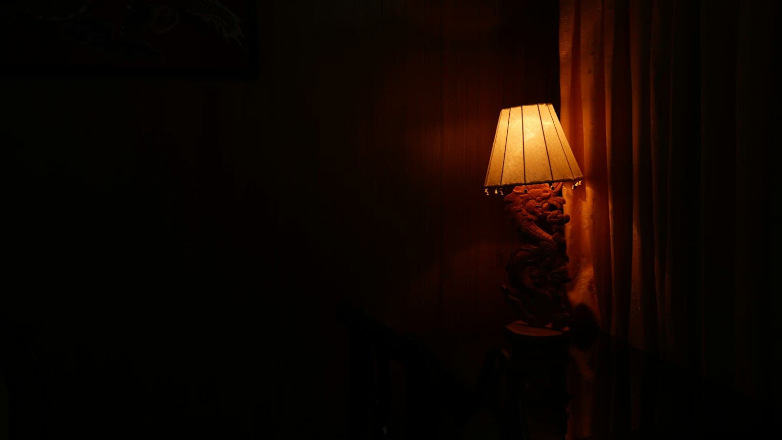 A single lit table lamp in an otherwise dark room